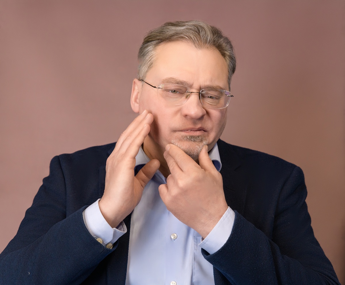 Man holding his jaw because of jaw joint pain, a common TMJ symptom